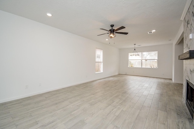 unfurnished living room featuring light wood-type flooring, ceiling fan, plenty of natural light, and a tile fireplace