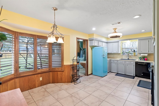 kitchen featuring decorative light fixtures, black dishwasher, sink, refrigerator, and gas water heater