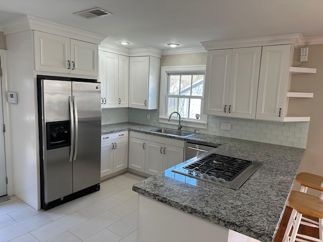 kitchen with appliances with stainless steel finishes, white cabinetry, sink, a kitchen breakfast bar, and kitchen peninsula