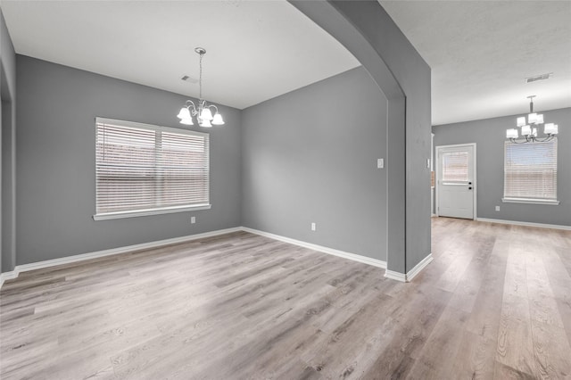 empty room with an inviting chandelier and light hardwood / wood-style flooring