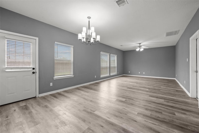 interior space with ceiling fan with notable chandelier and light hardwood / wood-style flooring