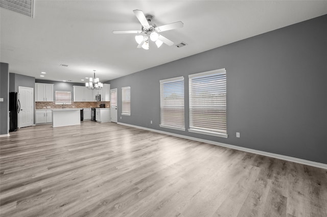 unfurnished living room featuring sink, ceiling fan with notable chandelier, and light wood-type flooring