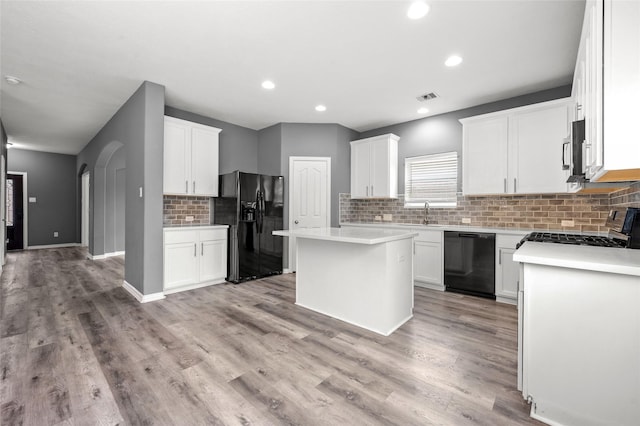 kitchen with tasteful backsplash, white cabinetry, a kitchen island, and black appliances