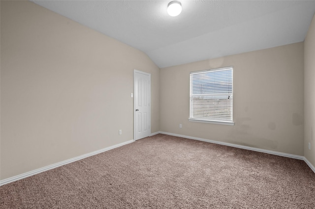 carpeted empty room with lofted ceiling