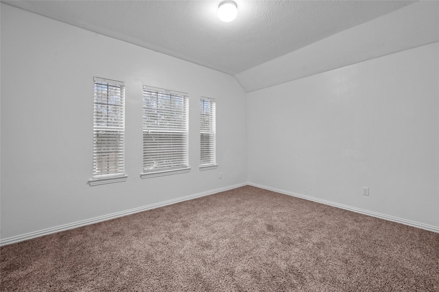 spare room featuring lofted ceiling, a textured ceiling, and carpet flooring