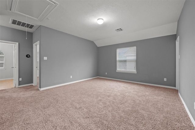 carpeted spare room featuring vaulted ceiling and a textured ceiling