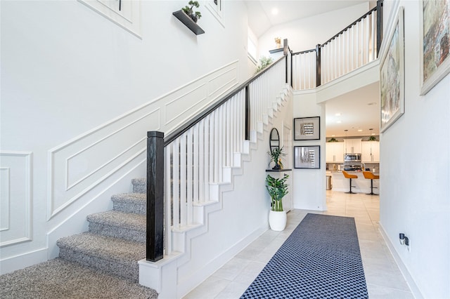 stairway with a towering ceiling and tile patterned floors