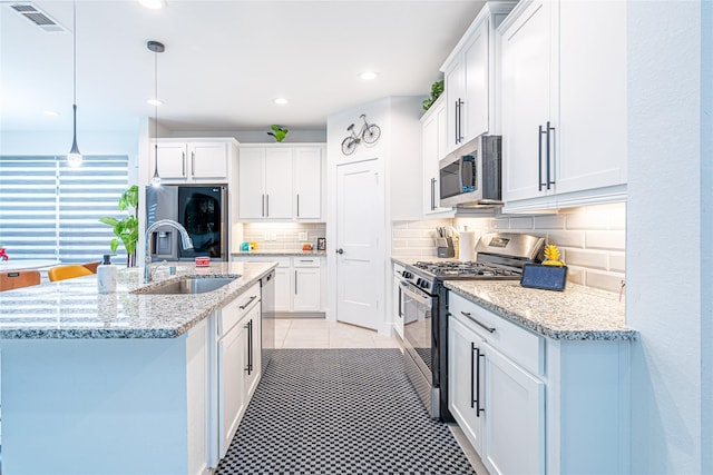 kitchen featuring white cabinetry, a center island with sink, appliances with stainless steel finishes, pendant lighting, and sink