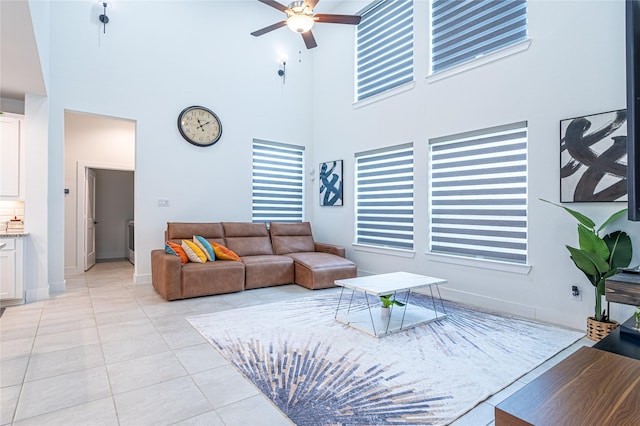 tiled living room featuring ceiling fan and a high ceiling