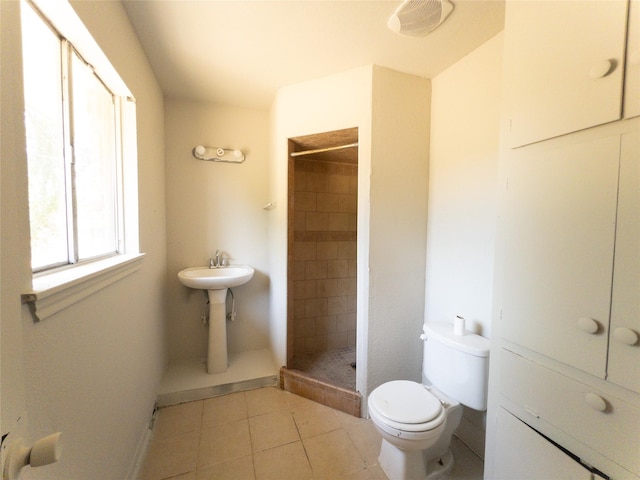 bathroom featuring toilet, tile patterned flooring, and tiled shower