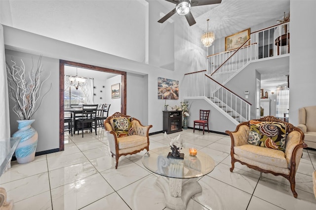 living room with ceiling fan with notable chandelier and a high ceiling