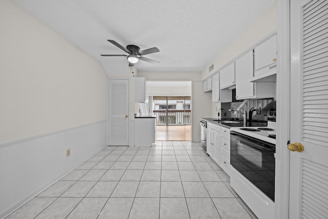 kitchen with a textured ceiling, stainless steel dishwasher, white cabinetry, electric range, and light tile patterned floors