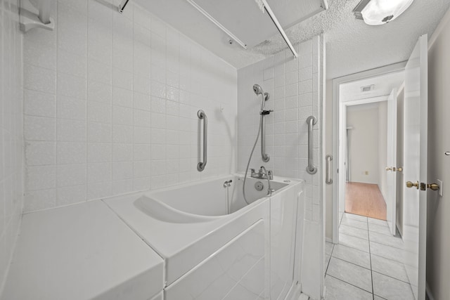 bathroom featuring a textured ceiling, tile patterned floors, and tiled shower / bath