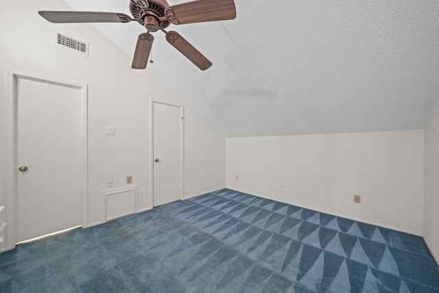 additional living space with ceiling fan, vaulted ceiling, a textured ceiling, and dark colored carpet