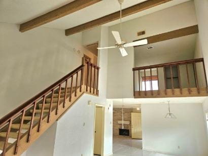 stairs with ceiling fan, beamed ceiling, and high vaulted ceiling