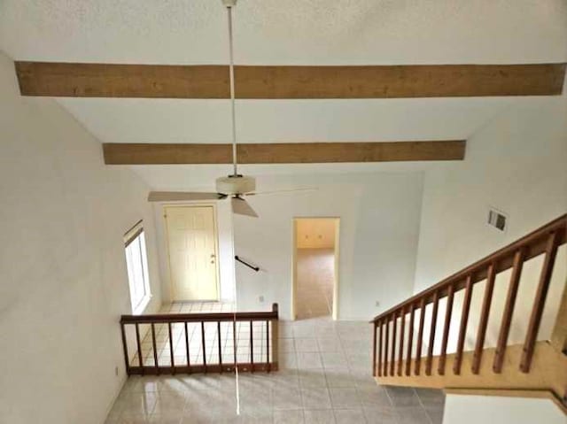 staircase with a textured ceiling, ceiling fan, tile patterned flooring, and lofted ceiling with beams