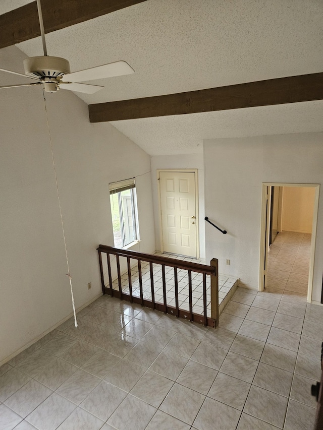 tiled spare room featuring lofted ceiling, ceiling fan, and a textured ceiling