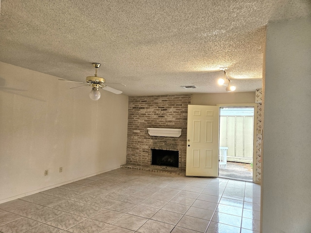 unfurnished living room featuring ceiling fan, light tile patterned flooring, a textured ceiling, and a fireplace