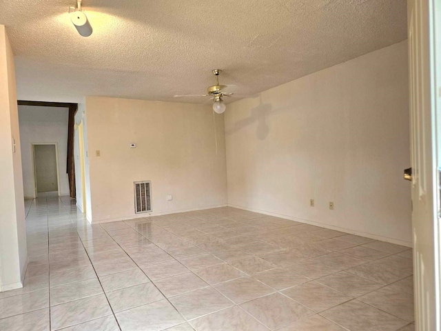 spare room featuring a textured ceiling, ceiling fan, and light tile patterned floors