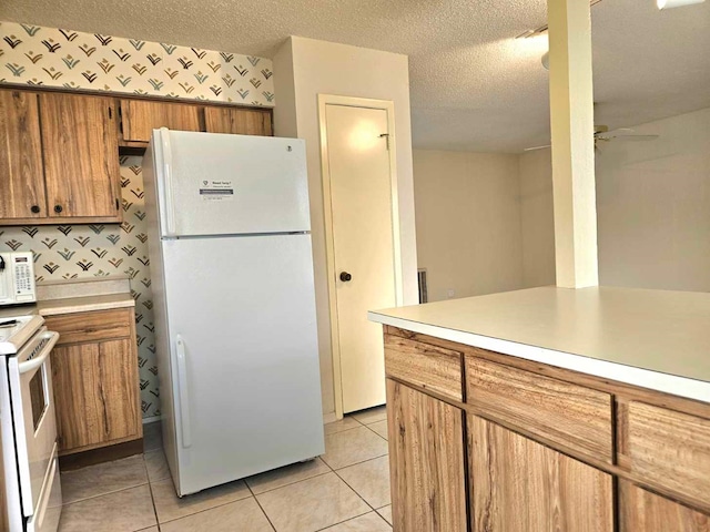 kitchen with a textured ceiling, ceiling fan, light tile patterned flooring, and white appliances