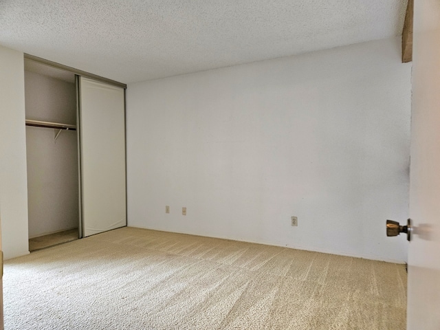 unfurnished bedroom with light colored carpet, a textured ceiling, and a closet