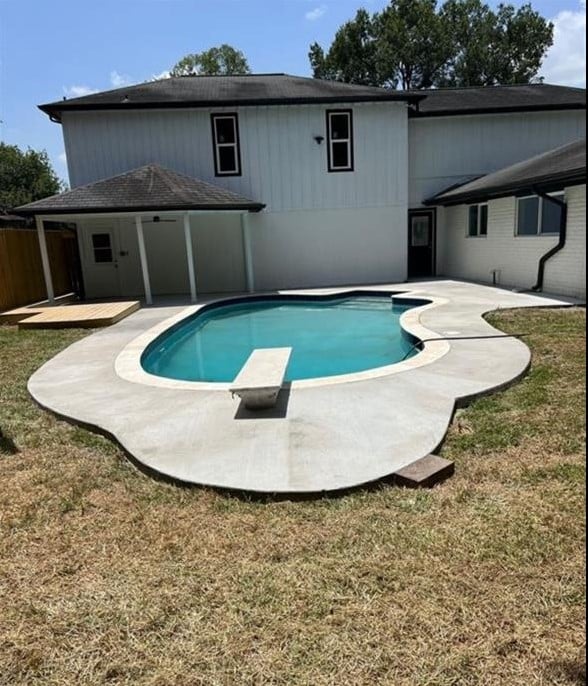 view of pool featuring a lawn, a diving board, and a patio