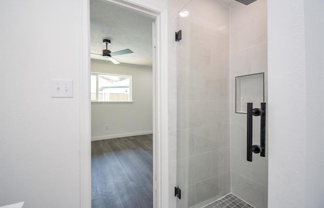 bathroom featuring ceiling fan, a textured ceiling, hardwood / wood-style flooring, and a shower with door