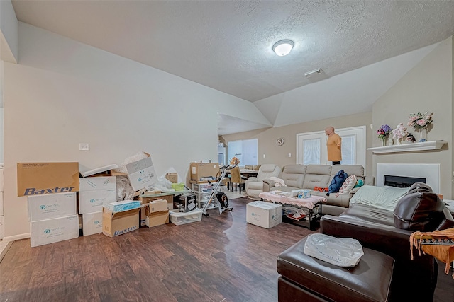 living room featuring lofted ceiling, dark wood-type flooring, a fireplace, and a textured ceiling