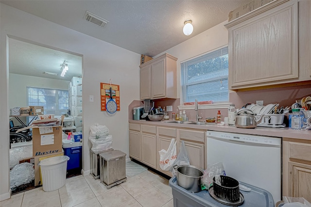 kitchen with light brown cabinetry, sink, light tile patterned floors, and dishwasher