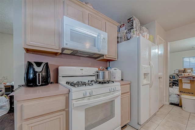 kitchen featuring light tile patterned flooring, light brown cabinetry, and white appliances