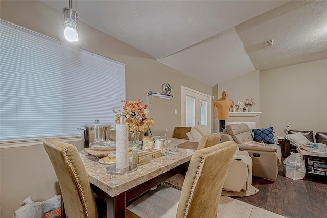 tiled dining room featuring a textured ceiling and vaulted ceiling