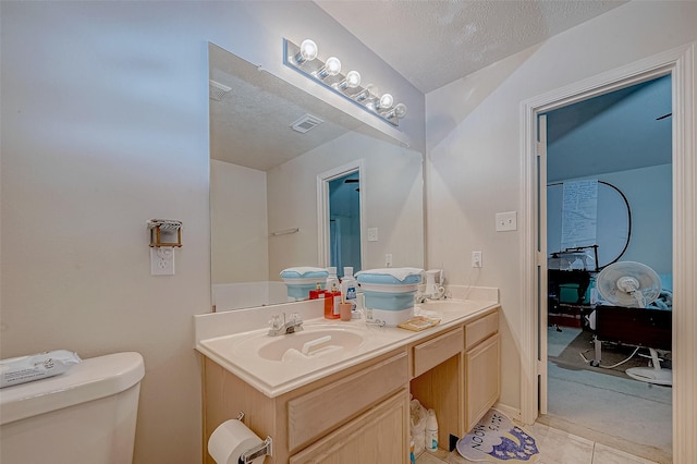 bathroom with toilet, vanity, tile patterned floors, and a textured ceiling