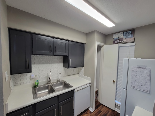 kitchen featuring sink, white appliances, dark hardwood / wood-style floors, tasteful backsplash, and a textured ceiling