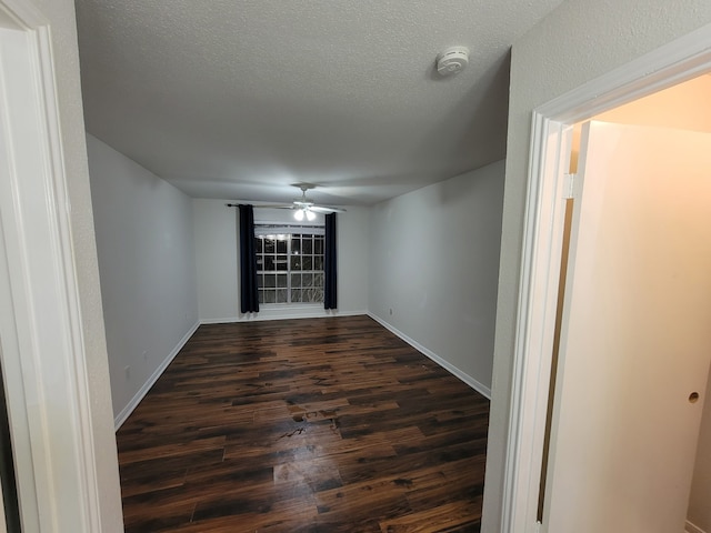 spare room featuring ceiling fan, dark wood-type flooring, and a textured ceiling