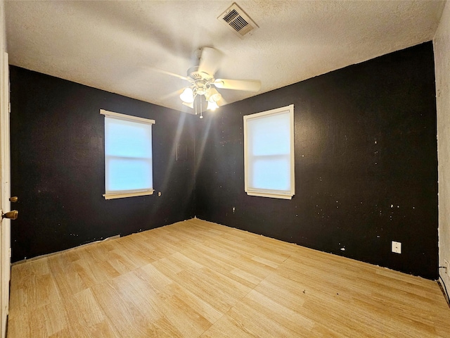 unfurnished room featuring ceiling fan, a wealth of natural light, a textured ceiling, and light wood-type flooring