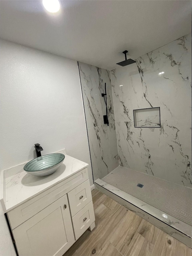 bathroom featuring wood-type flooring, a tile shower, and vanity