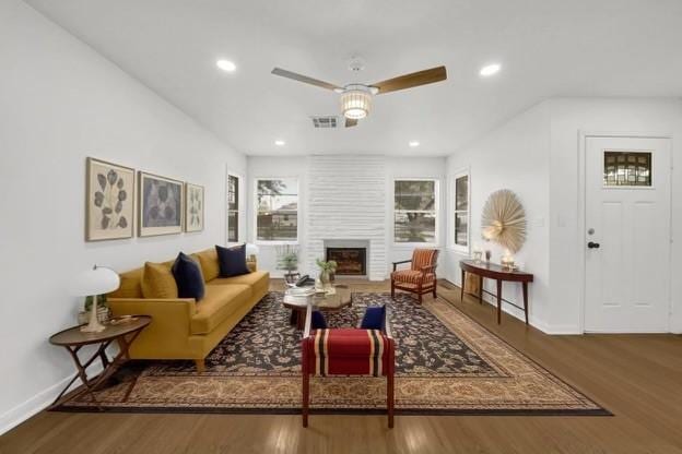 living room featuring hardwood / wood-style flooring, a large fireplace, and ceiling fan