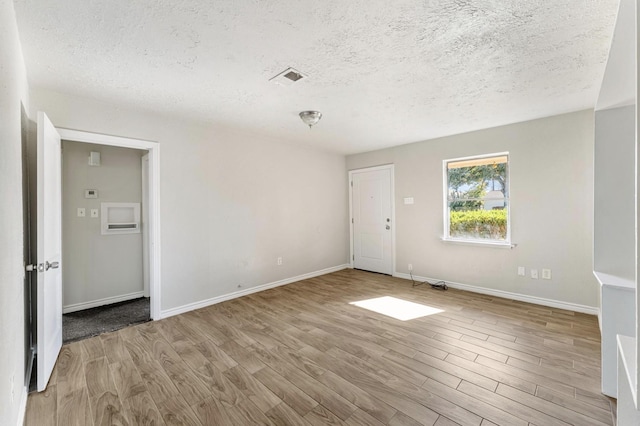 spare room with a textured ceiling and light hardwood / wood-style flooring