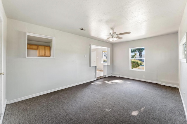 empty room featuring a textured ceiling, ceiling fan, and dark colored carpet