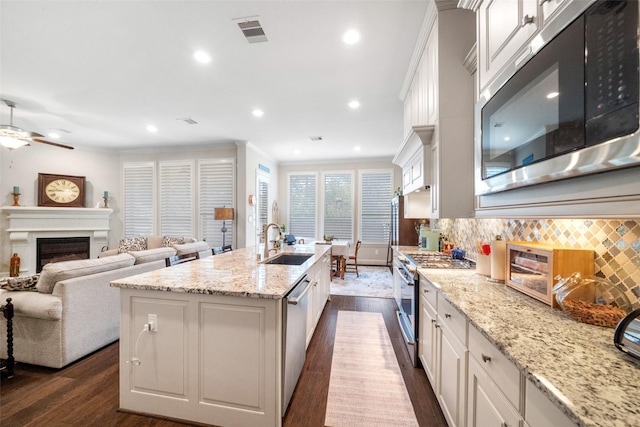 kitchen featuring sink, appliances with stainless steel finishes, a kitchen island with sink, ornamental molding, and white cabinets