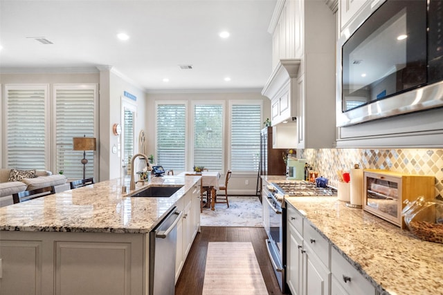 kitchen featuring light stone countertops, appliances with stainless steel finishes, sink, and a center island with sink