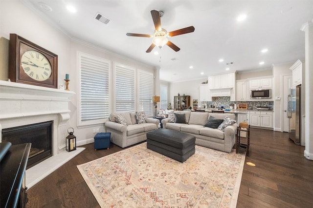 living room with crown molding, dark hardwood / wood-style floors, and ceiling fan