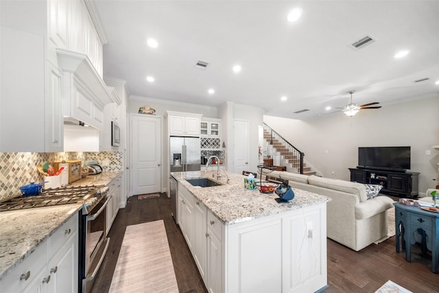 kitchen with sink, white cabinetry, stainless steel appliances, a kitchen island with sink, and decorative backsplash