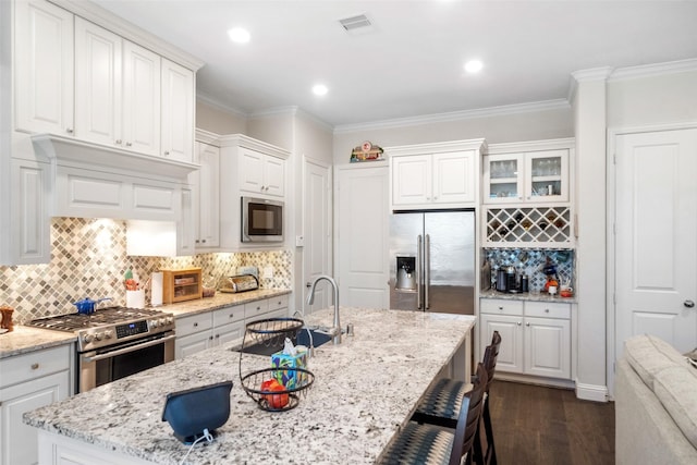 kitchen featuring crown molding, appliances with stainless steel finishes, white cabinetry, dark hardwood / wood-style floors, and light stone countertops