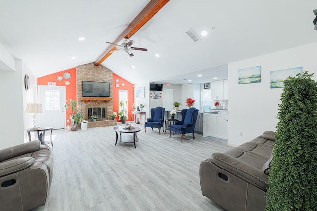 living room with ceiling fan, a fireplace, light hardwood / wood-style flooring, and vaulted ceiling with beams