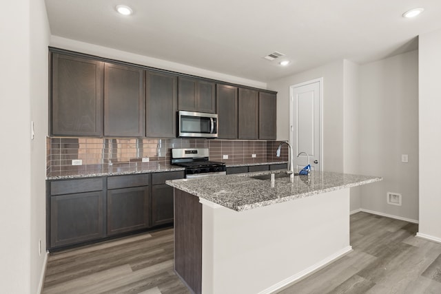 kitchen featuring light hardwood / wood-style floors, stainless steel appliances, light stone counters, dark brown cabinetry, and sink