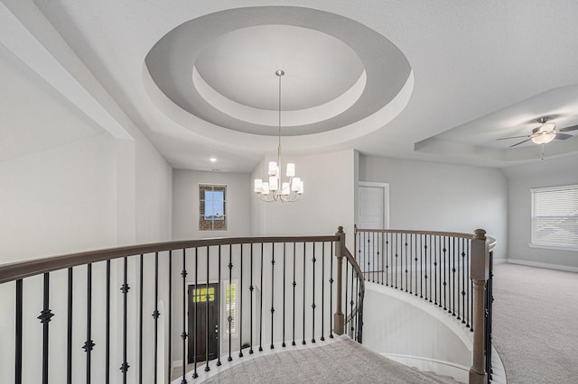 stairway with carpet, a healthy amount of sunlight, and a tray ceiling