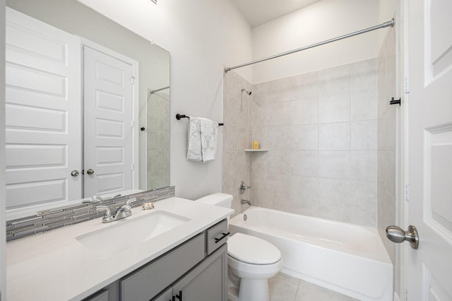 full bathroom featuring tiled shower / bath, tile patterned floors, vanity, tasteful backsplash, and toilet