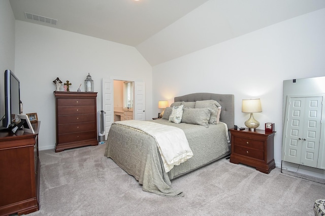 bedroom with lofted ceiling, light colored carpet, and ensuite bathroom