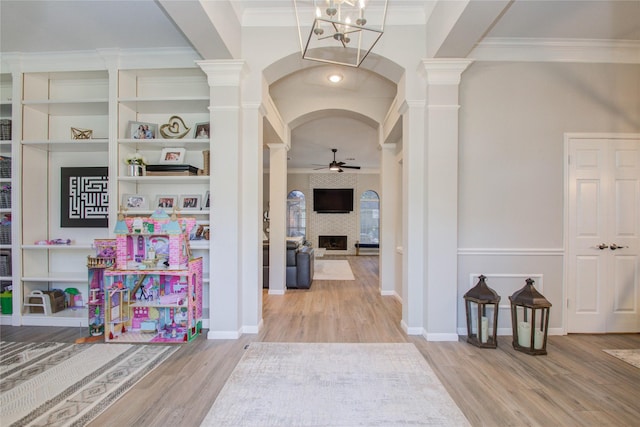 hallway featuring an inviting chandelier, crown molding, hardwood / wood-style flooring, and decorative columns